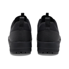 A pair of black slip-on sneakers shown from the back, featuring a textured fabric upper and thick black soles, set against a plain white background.