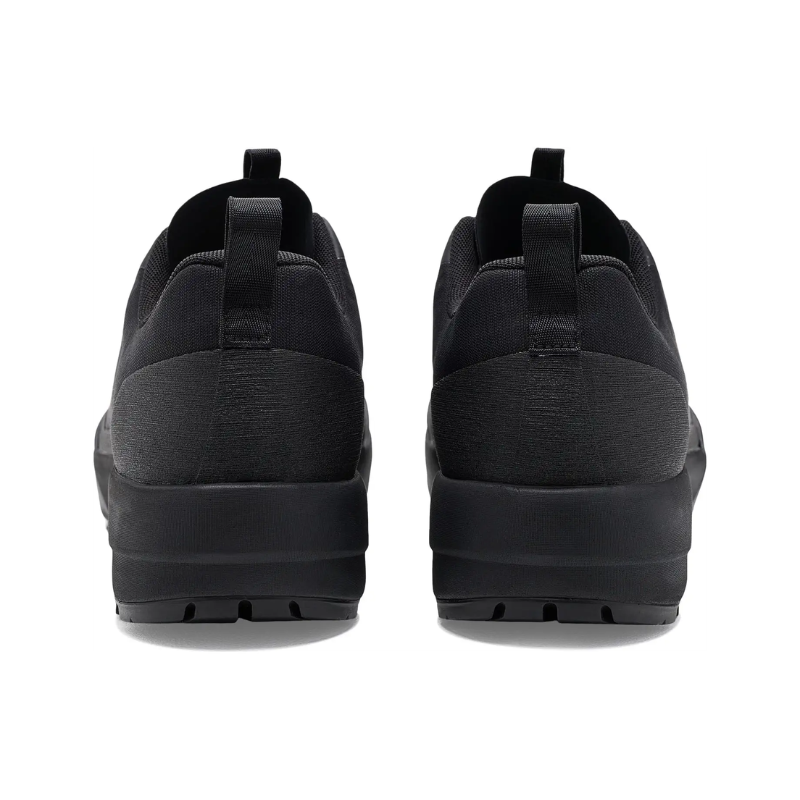 A pair of black slip-on sneakers shown from the back, featuring a textured fabric upper and thick black soles, set against a plain white background.
