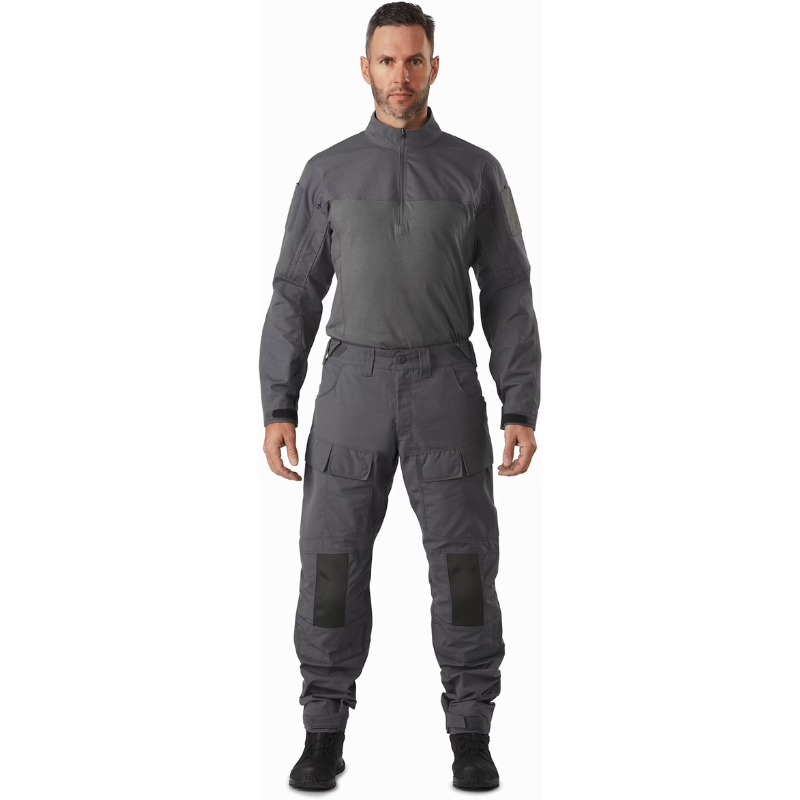 Full body view of operator wearing the Arc’teryx PRO Assault Combat Shirt, designed for body armor integration and direct action missions. Built with no melt/no drip NYCO Cordura® ripstop and Cyberknit jersey, this tactical base layer features a zip neck, arm pockets, and articulated fit for mobility under kit.