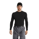 A man wearing a black long-sleeve performance base layer shirt, black beanie, and gray pants, standing against a plain white background.