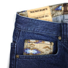 Close-up of blue jeans with a patterned patch and label on a white background