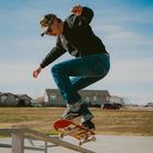 Person skateboarding on a rail with houses and cars in the background