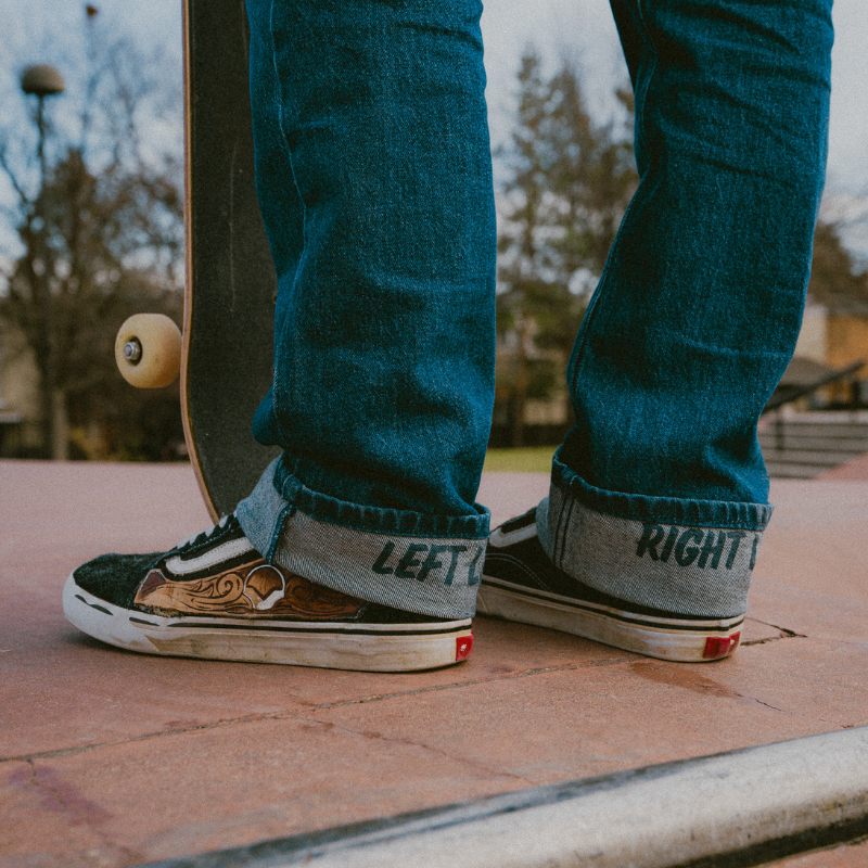 Person wearing blue jeans and sneakers with 'LEFT' and 'RIGHT' labels, standing by a skateboard.