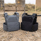 Black and Grey Black Crest Enforcer Plate Carriers shown on the ground during a range day, displaying their clean LaserCut profiles, low-profile shoulders, and FirstSpear Tubes-compatible chassis with no attachments installed. Highlights the streamlined footprint, lightweight construction, and modular blank configuration for users comparing plate carrier silhouettes, setup options, and real-world range performance.