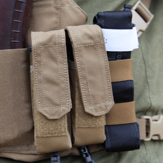 Blue Force Gear Tourniquet NOW Strap securing a CAT tourniquet to a tactical kit alongside magazine pouches, providing rapid-access medical gear retention on a MOLLE loadout.