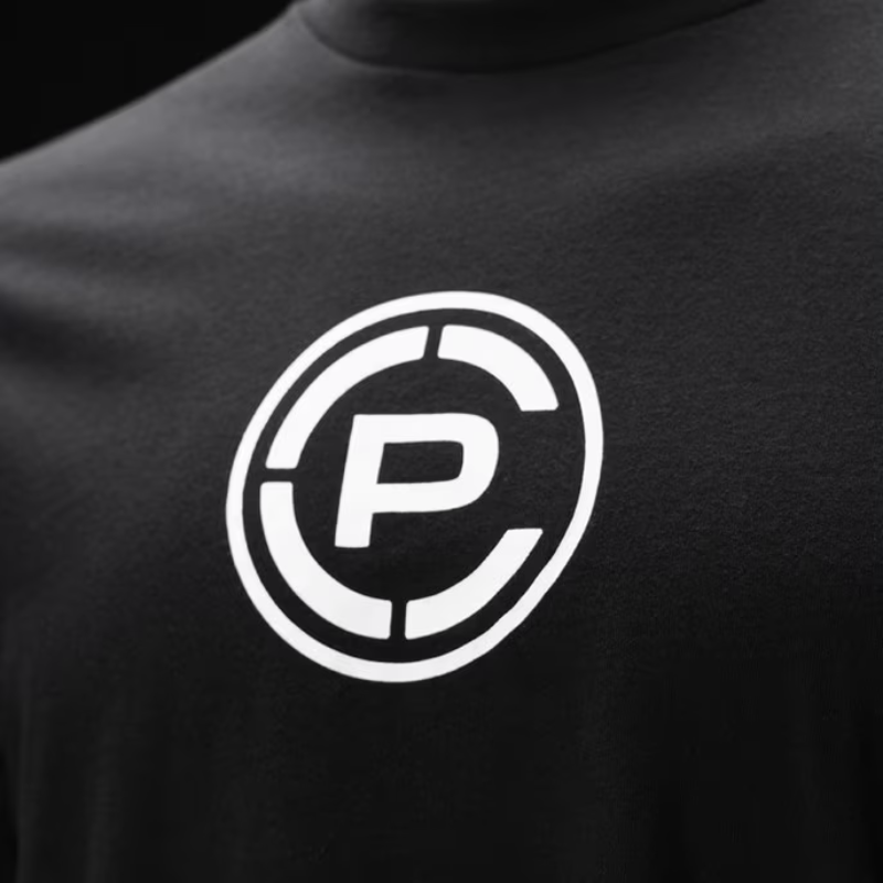 Close-up of a black crewneck t-shirt featuring a white circular logo with a stylized letter 'CP' on the chest.