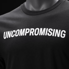 A close-up of a black crewneck t-shirt displayed on a mannequin torso, featuring the word 'UNCOMPROMISING' printed across the chest in bold white capital letters.