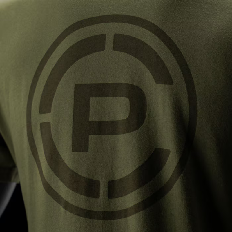 Close-up of an olive green t-shirt featuring a large, tonal dark brown circular 'CP' logo on the chest.
