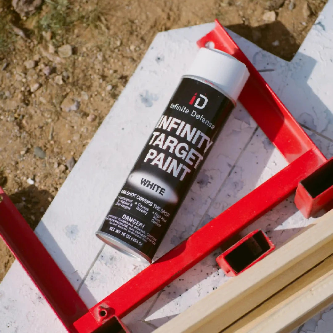 Can of Infinity Target Paint on a red stand with a concrete surface and gravel in the background