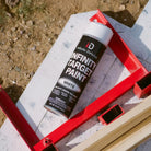 Can of Infinity Target Paint on a red stand with a concrete surface and gravel in the background