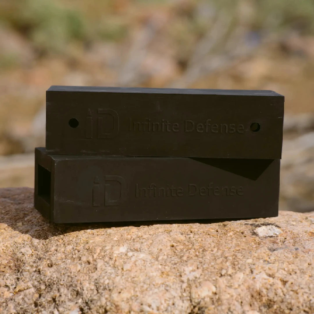 Two black 'Infinite Defense' products on a rock with a blurred natural background