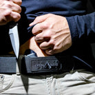 User accessing a concealed storage compartment built into the Dynamis Alliance 1.75 Inch LOPRO Belt for discreet everyday carry organization.