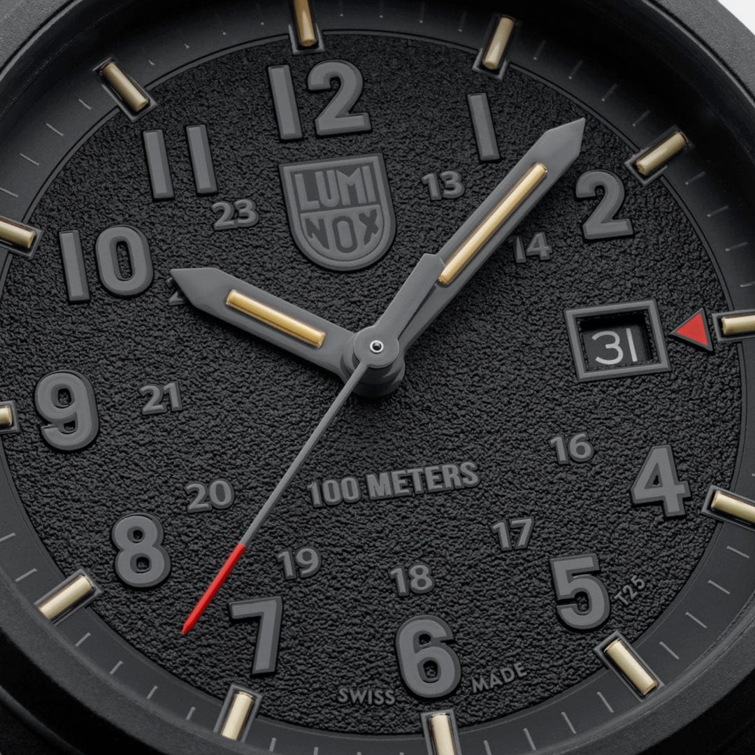 Macro close-up of the Luminox Atacama Field 1961 dial, highlighting the textured blackout face, stealth hour numerals, red arrow date indicator, and red tipped second hand designed for high contrast readability in tactical and outdoor environments.