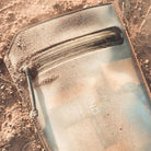 Magpul DAKA Volume Pouch Flat Dark Earth placed in dirt outdoors highlighting durable waterproof construction