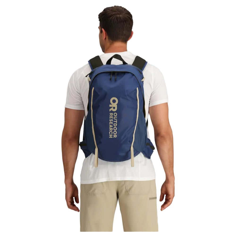 Lifestyle image of the Outdoor Research Adrenaline Day Pack 30L in Cenote navy blue, shown being worn with ergonomic straps and hip belt for secure, comfortable carry on alpine missions, day hikes, and fast-and-light adventures.