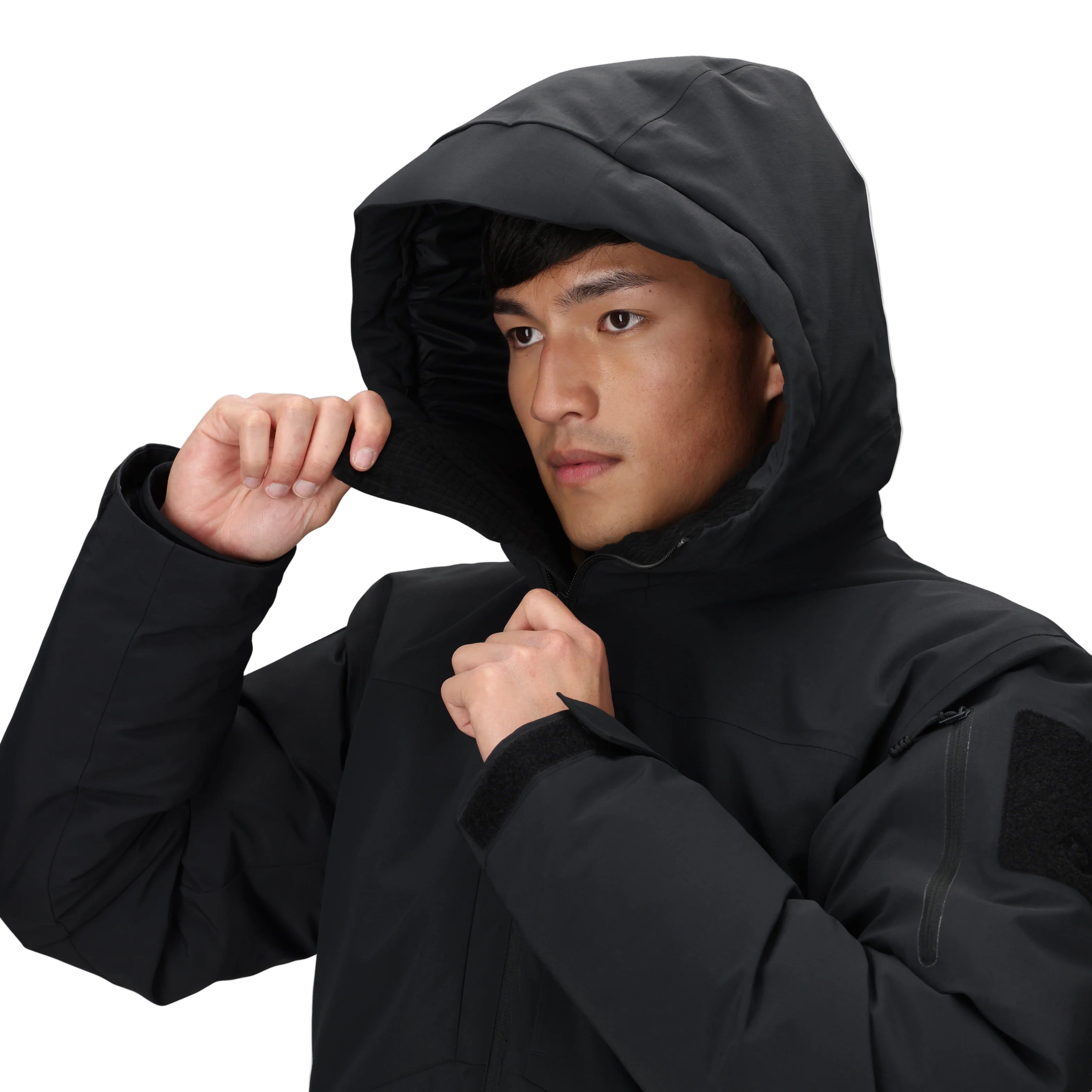 Detail view of the Outdoor Research Allies Colossus II Parka showing a model pulling the insulated hood up and zipping the waterproof YKK® AquaGuard front closure, highlighting extreme cold weather parka design for Arctic missions, military use, and survival in subzero conditions.