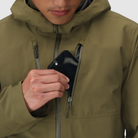 Detail shot of the Outdoor Research Allies Mountain II Jacket in Ranger Green showing the front pocket being used, highlighting the tactical storage layout, waterproof AscentShell construction, and Cordura ripstop durability designed for military, law enforcement, and alpine professionals needing fast access to mission essential gear.
