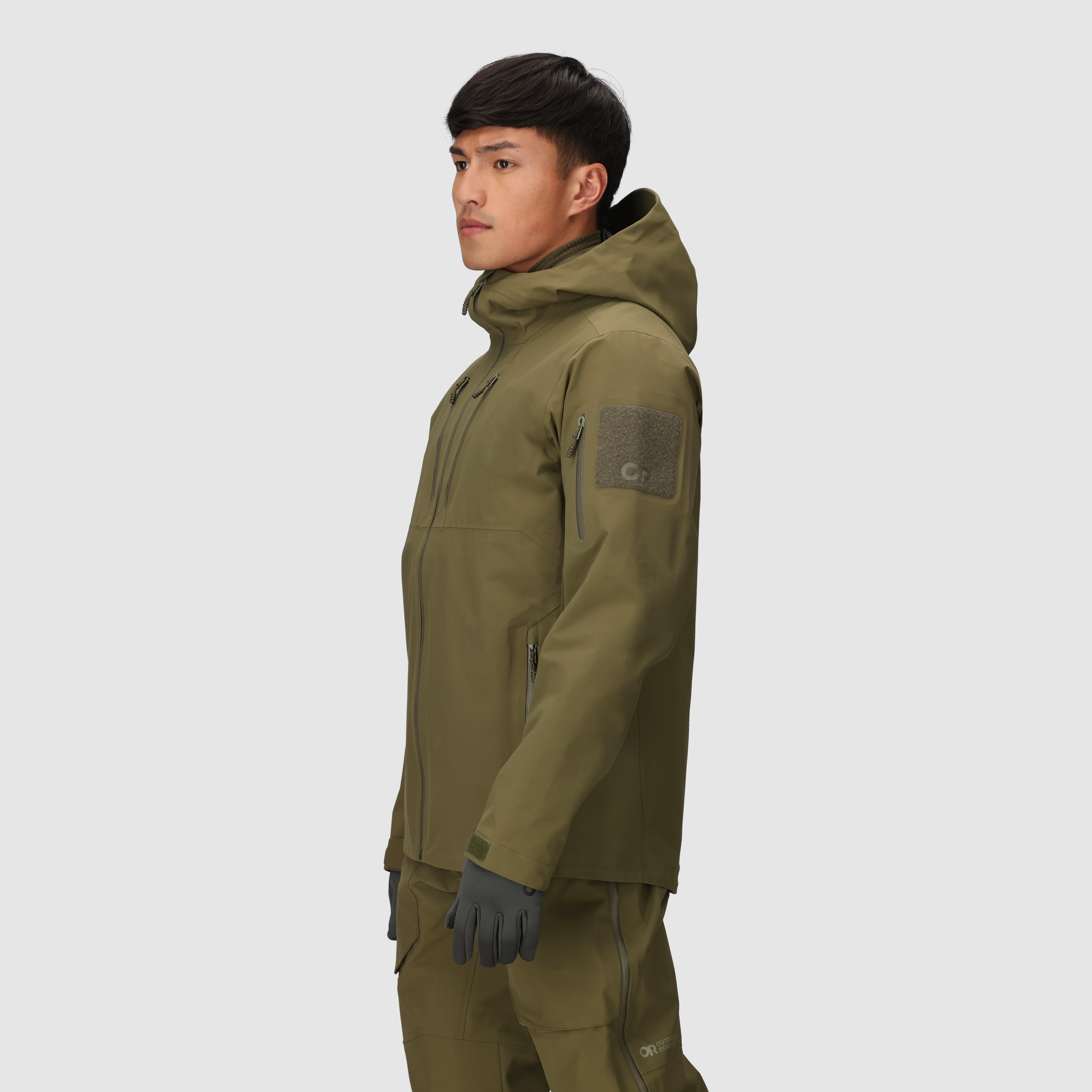 Three-quarter view of the Outdoor Research Allies Mountain II Jacket in Ranger Green showing the AscentShell waterproof construction, Cordura ripstop durability, articulated combat fit, and helmet compatible hood designed for military, law enforcement, and alpine professionals needing rugged weather protection and full mobility.