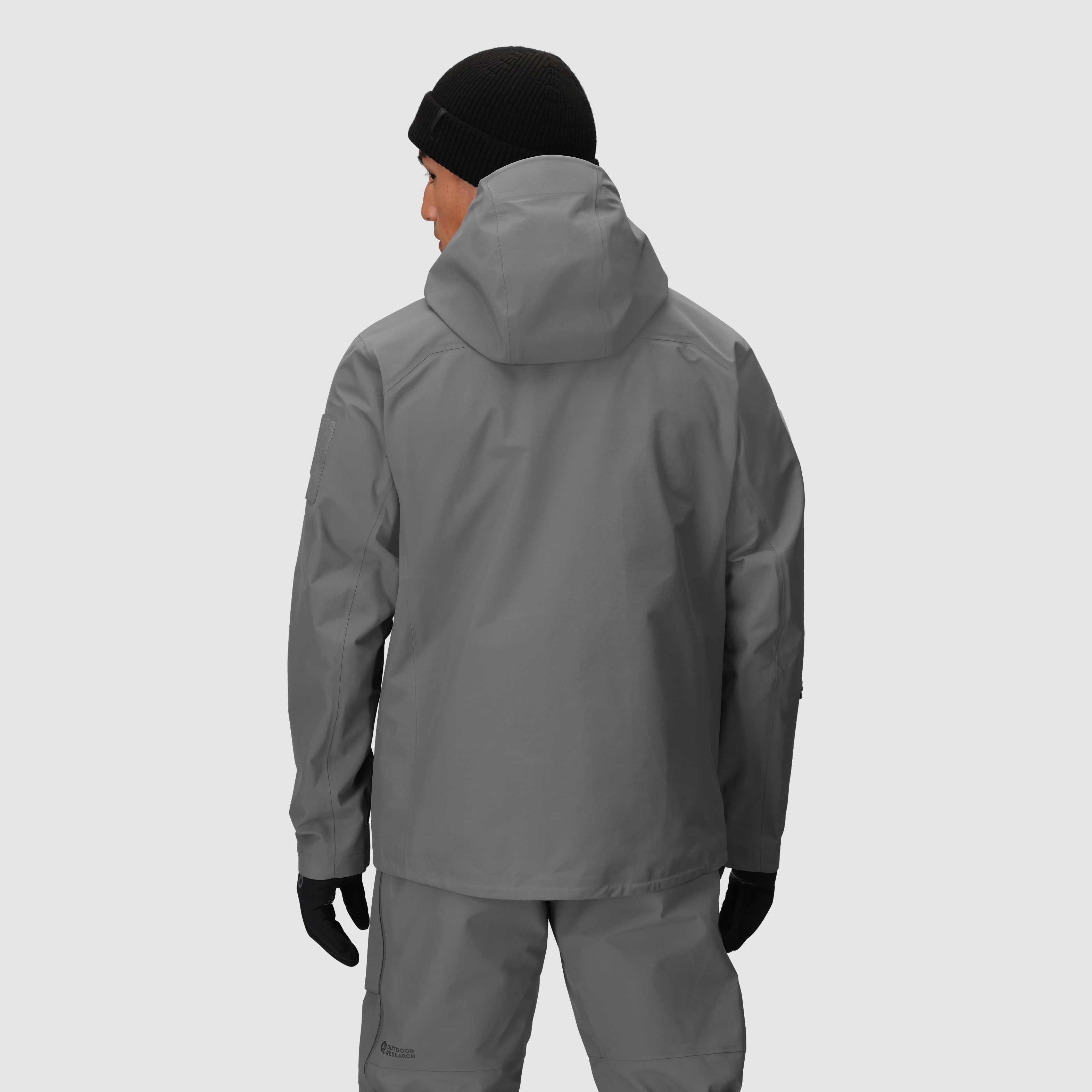 Back view of the Outdoor Research Allies Mountain II Jacket in Wolf Grey showing the durable Cordura ripstop shell, helmet compatible hood, and full coverage AscentShell waterproof design built for military, law enforcement, and alpine professionals needing rugged storm protection and unrestricted mobility.
