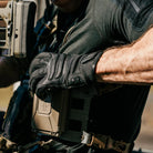 Operator wearing Outdoor Research Ironsight II FR Gloves in Black during field operations, flame resistant Nomex and Kevlar tactical duty gloves integrated into full combat gear setup for military missions, range training, and law enforcement duty applications