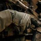 Operator wearing Outdoor Research Ironsight II FR Gloves in Ranger Green during field operations, flame resistant Nomex and Kevlar tactical duty gloves integrated into combat gear setup for military missions, range training, and law enforcement duty applications