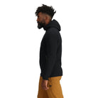 Side view of the Outdoor Research Vigor Plus Fleece Hoodie in black, shown on a model to highlight the athletic fit, stretch side panels, and ergonomic hood design built for layering and active cold-weather pursuits.