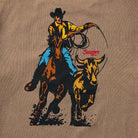 Close-up of the back graphic on the Rodeo Series Tee in Pigment Brown, highlighting the bold Rodeo artwork printed on premium pigment-dyed cotton. Shows the textured, vintage-inspired ink detail and worn-in aesthetic. Ideal for users searching for Western graphic tees, pigment-dyed shirt designs, or detailed rodeo artwork apparel with a broken-in look.