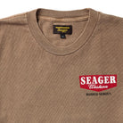 Close-up of the Rodeo Series Tee in Pigment Brown showing the Seager chest graphic printed on premium pigment-dyed cotton. Highlights the vintage wash, textured ink detail, and heavier knit fabric that gives the shirt its broken-in look and everyday durability. Ideal for users searching for Western chest-print tees, Seager-inspired graphic shirts, or pigment-dyed apparel with a rugged, worn-in aesthetic.
