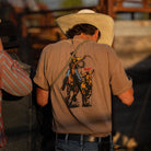 Lifestyle photo of the Rodeo Series Tee in Pigment Brown being worn, showing the vintage pigment-dyed finish, relaxed true-to-size fit, and bold Western Rodeo graphic. Highlights the heavier knit cotton construction and broken-in look ideal for everyday wear, range days, or casual hangs. Perfect for users searching for rugged Western tees, pigment-dyed shirts, or premium graphic tees with a lived-in aesthetic.