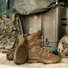 Lifestyle photo of the Salomon FORCES Quest 4D 2 High GTX boots in Coyote staged with military equipment showing the waterproof GORE TEX tactical mountain design built for military operations, rugged terrain, extended rucking, and field missions.