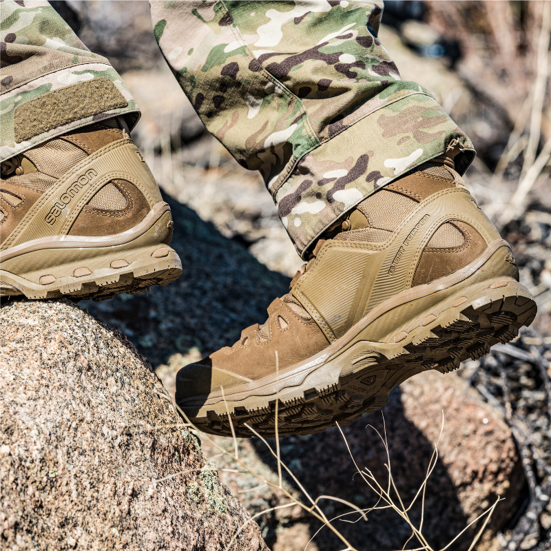 On body view of the Salomon FORCES Quest 4D 2 High GTX boots being worn while trekking in a military capacity showing the waterproof GORE TEX design, high cut ankle support, and 4D Advanced Chassis stability built for rugged terrain, extended rucking, and field missions.