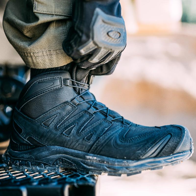 Salomon XA FORCES MID Black tactical boots worn in a tactical situation | Lightweight military combat footwear with Quicklace lacing system reinforced chassis and rugged all terrain outsole built for law enforcement and military operators on mission