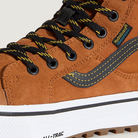 Brown boot with black laces and white sole on a light gray background