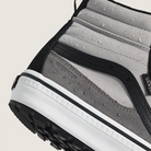 Close-up of a gray sneaker with black and white sole on a light beige background