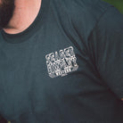 Close-up of the Seager Rattler Tee in Vintage Black worn on a model, showing the left chest rattlesnake graphic print on durable 100% cotton, a western-inspired tee built for rugged everyday wear.