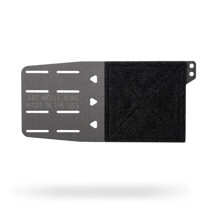 A black and dark gray split-panel mounting plate with a textured velcro-like black section on the right and a metal gray section on the left with cutouts and embossed text reading 'ARC-MOLLE WING MADE IN THE USA'.