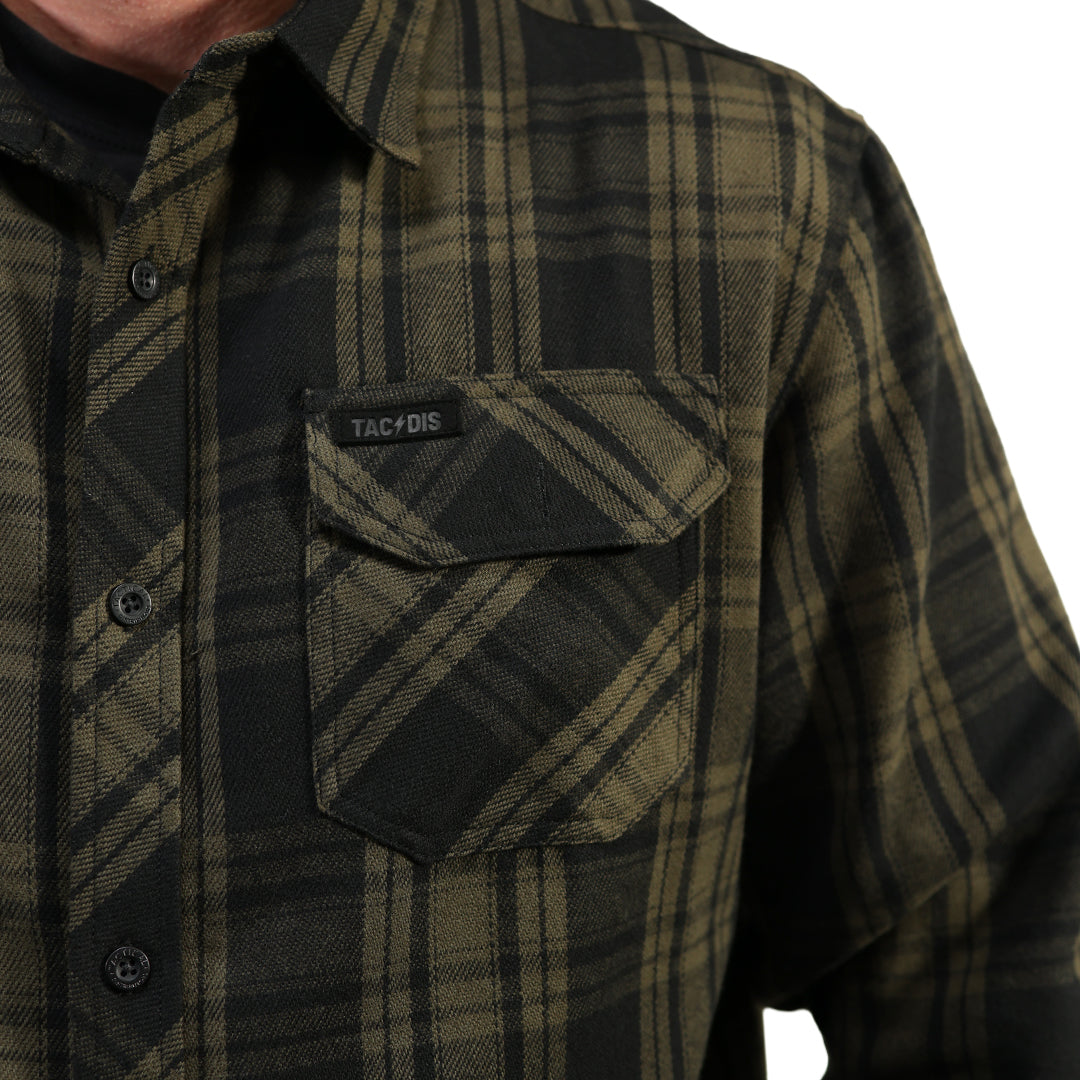 Close-up of a man wearing a plaid button-up shirt in dark olive green and black, featuring a chest pocket with a flap and a visible Tac-Dis brand label.