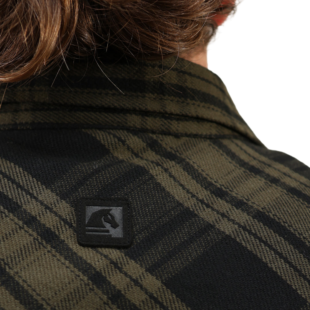Close-up of the back of a person wearing a dark olive green and black plaid flannel shirt, featuring a small black square patch with a horse logo on the upper back.