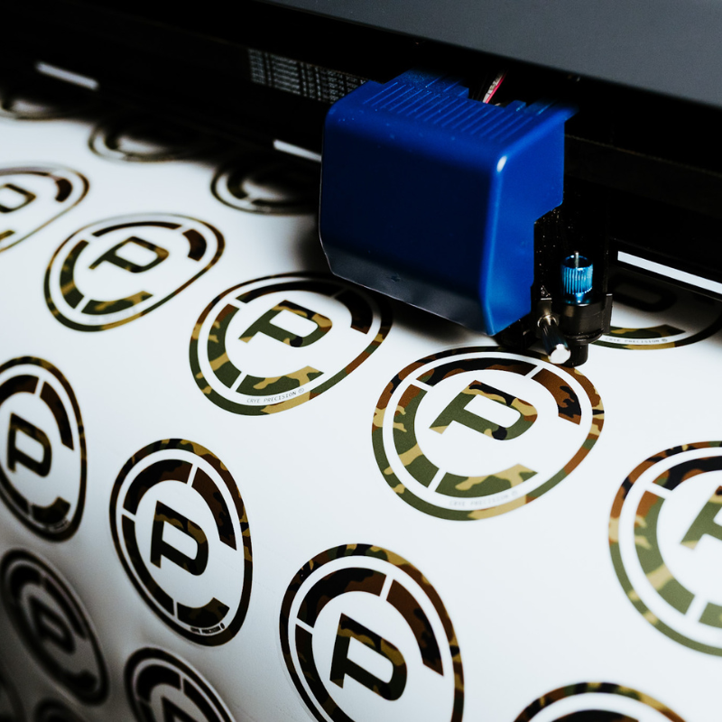 Close-up of TD x Crye Precision M81 Woodland stickers in production, highlighting the locally printed collaboration artwork and limited-edition manufacturing process.
