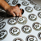 TD x Crye Precision M81 Woodland stickers being printed during a small-batch production run in Virginia Beach, showcasing the matte-finish collaboration design.