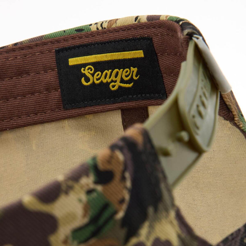 Camouflage hat with 'Seager' logo on a white background