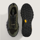 Green and black hiking shoe with textured sole on a light gray background