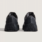 Black sneakers with textured soles on a light gray background