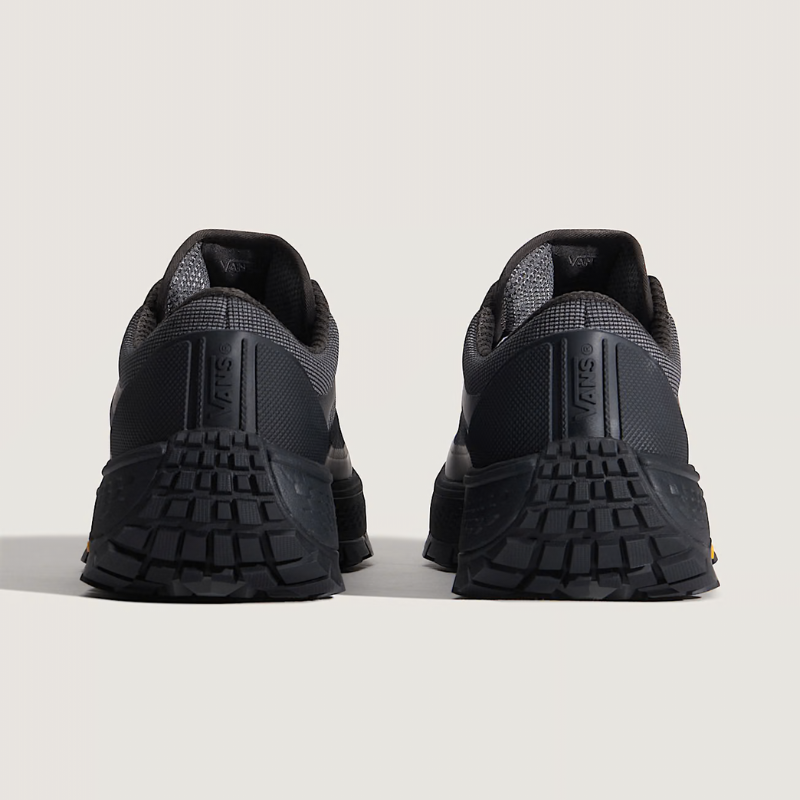 Black sneakers with textured soles on a light gray background