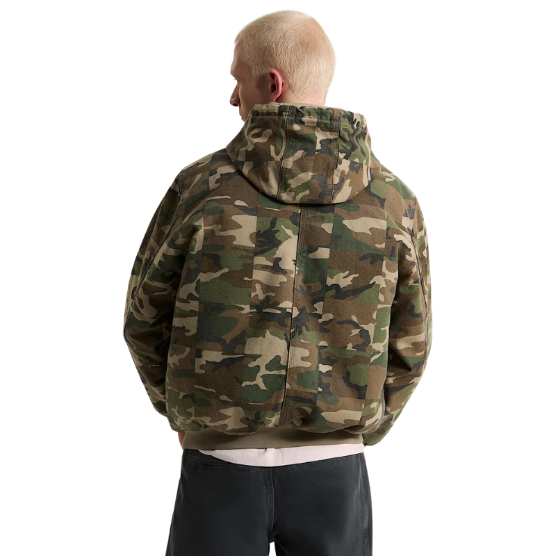 A man viewed from behind wearing a camouflage hooded sweatshirt and dark pants against a plain white background.