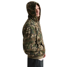 A person shown in side profile wearing a camouflage pullover hoodie against a plain white studio background.