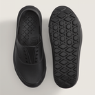 Black slip-on shoes with textured sole on a light gray background