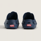 Navy blue clogs with a red Vans logo on a light beige background