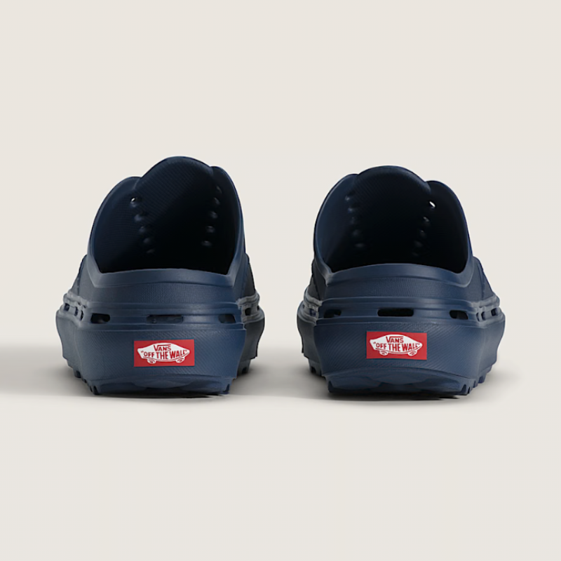 Navy blue clogs with a red Vans logo on a light beige background