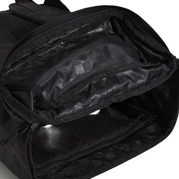 Vans Omit Backpack shown unzipped while laid on its side displaying the interior pockets, mesh organizers, and padded laptop sleeve inside the rugged Cordura 28 liter main compartment built for daily carry and mission ready use.